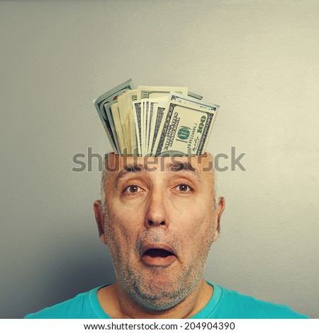surprised senior man having open head with money over grey background