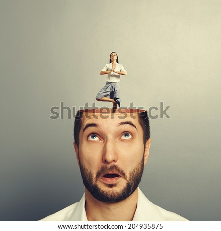 amazed young man with open head. calm yoga businesswoman standing into the head. photo over grey background