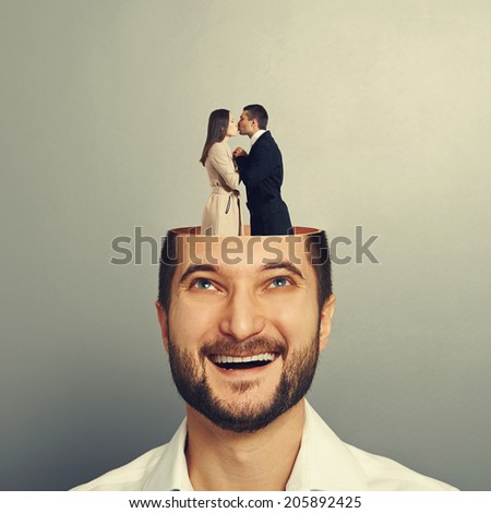 happy young businessman with open head. couple in love kissing and standing in the man\'s head. photo over grey background