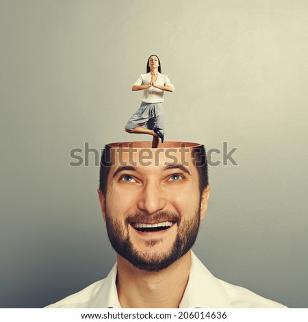 smiling man with open head looking up at calm yoga woman over grey background