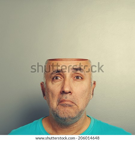 sad senior man with open head over grey background