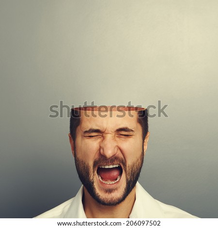 screaming man with open head over grey background