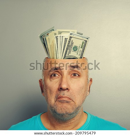 depressed senior man having open head with money over grey background