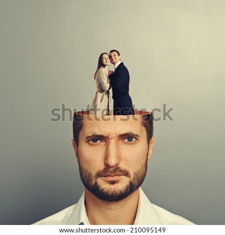 young businessman with open head. couple in love embracing and standing in the man\'s head. photo over grey background