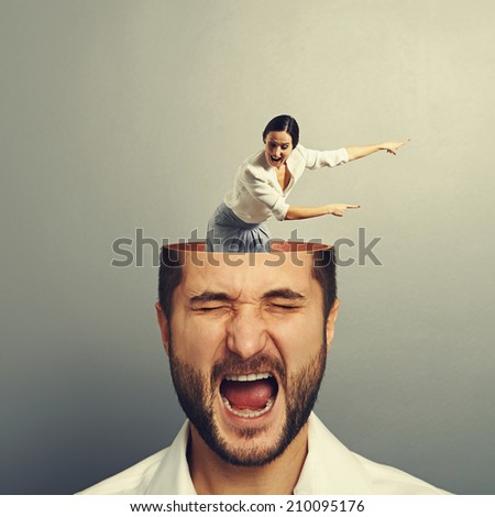 stressed man with open head. young screaming woman standing into the head, looking at the man and showing the direction. photo over grey background