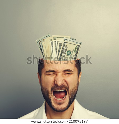 screaming young businessman with money in the head over grey background
