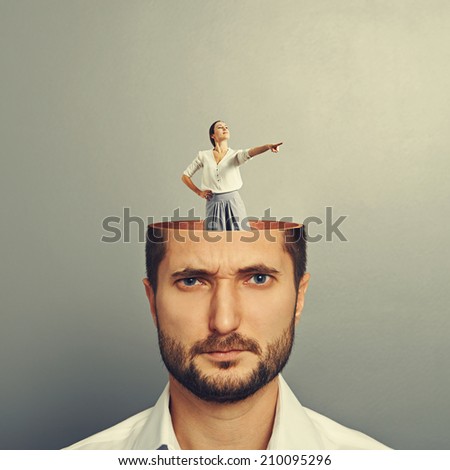 displeased businessman with open head. young smiley businesswoman standing into his head and showing the direction. photo over grey background