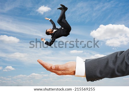 big palm catching small frightened businessman over blue sky
