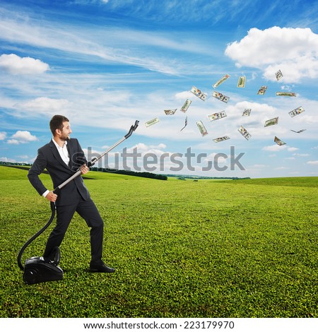 happy laughing businessman holding vacuum and catching paper money at outdoor