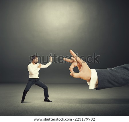 concept photo of conflict between subordinate and boss. angry young businessman ready for fight with big flick of his boss. photo in the dark room