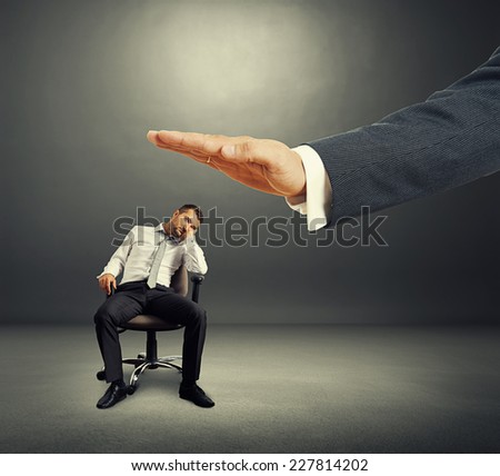 big hand ready to hit lazy businessman on the office chair. photo over dark background
