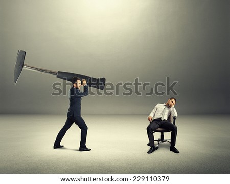 dissatisfied boss holding big hammer and screaming at lazy worker. photo in the dark room