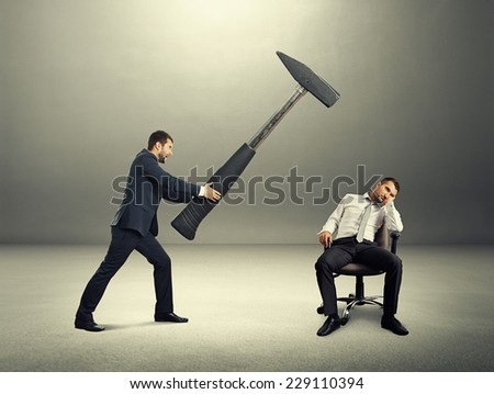 displeased boss holding big hammer and screaming at lazy worker. photo in the dark room