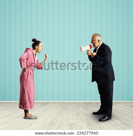 angry senior man in suit holding megaphone and screaming at dissatisfied woman in pink dressing gown. photo in the room
