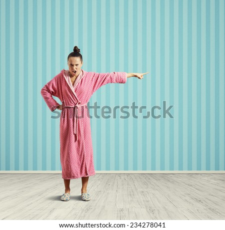 angry housewife standing in the room, screaming and pointing at empty copyspace