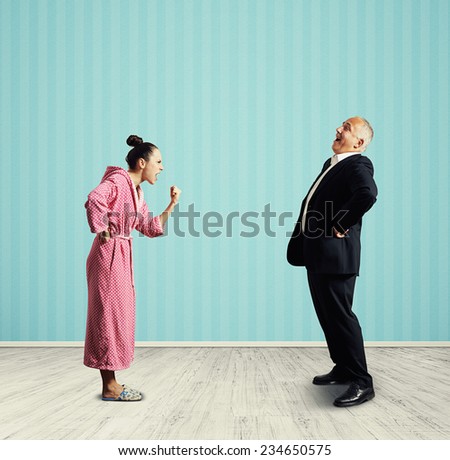 emotional woman in pink dressing gown screaming and showing fist laughing senior man in suit