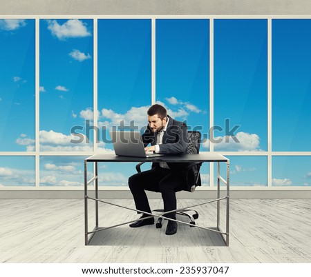 concentrated businessman working with laptop in the light office with big windows