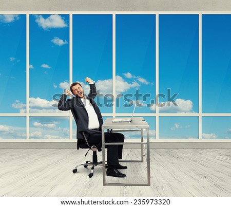fatigued businessman yawning and stretching oneself in the light office with big windows