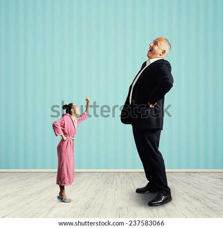 angry small woman screaming at big laughing senior man