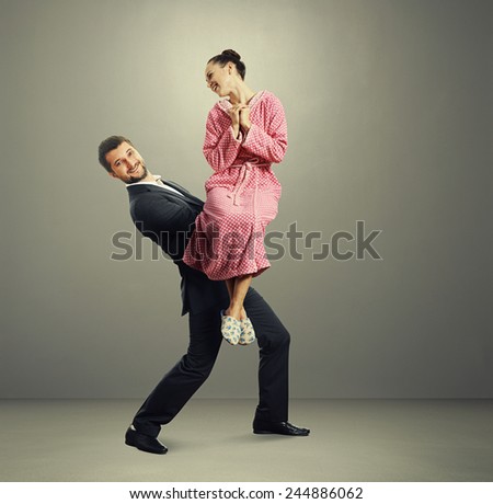 happy couple over grey background. smiley man holding on the hands his woman and looking at camera