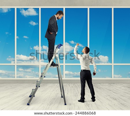 discontented businessman standing on stepladder and looking at angry screaming man. photo in the room with big windows