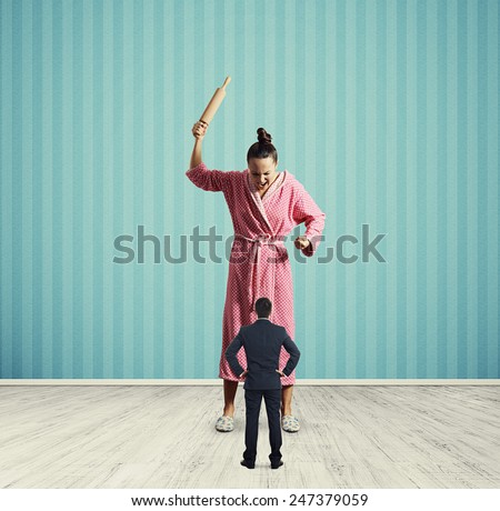 angry housewife screaming at small husband. photo in room with blue wall