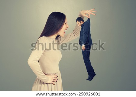 emotional screaming woman looking at small young man over dark background