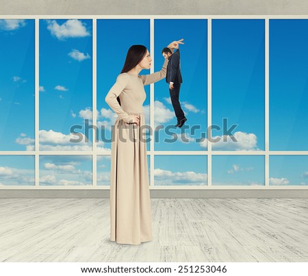 serious pretty woman looking at sad small man. photo in empty room with big windows