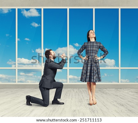 sad man looking at young attractive woman and asking for forgiveness. photo in empty room with big windows