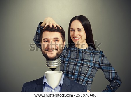 smiley woman fixing man over dark background