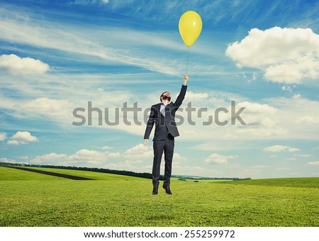 laughing man flying with yellow balloon