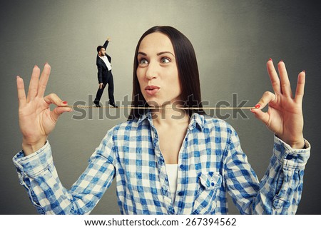 amazed woman looking at small man on the rope over dark background