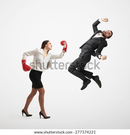 angry businesswoman in formal wear and red boxing gloves punching businessman over light grey background