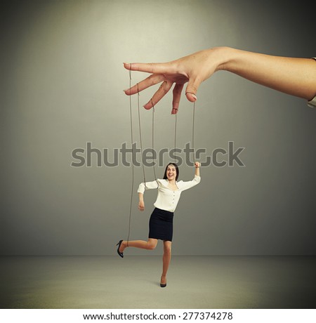 womans hand manipulating puppet over dark background