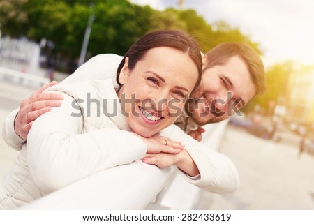 urban photo of smiley young couple in love looking at camera