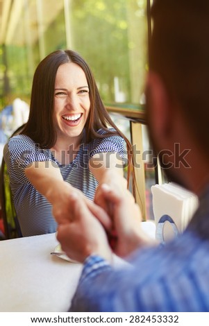 happy loving couple on date at the restaurant. young excited woman laughing and holding hands by man