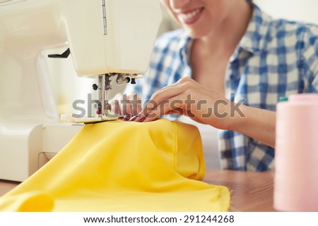 smiley woman sewing on sewing-machine. focus on sewing-machine