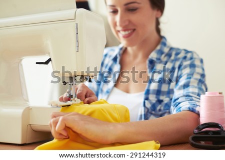 seamstress sewing yellow dress. focus on sewing-machine