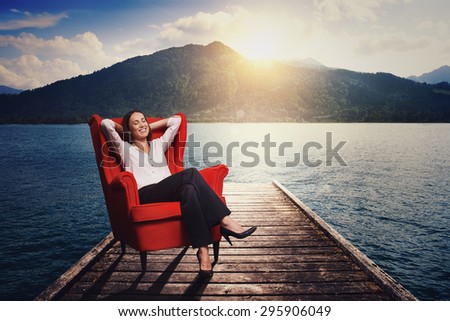 smiley woman resting and dreaming on the red chair on wood moorage over beautiful landscape