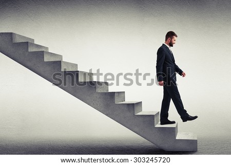 smiley businessman in formal wear walking down the steps over grey background