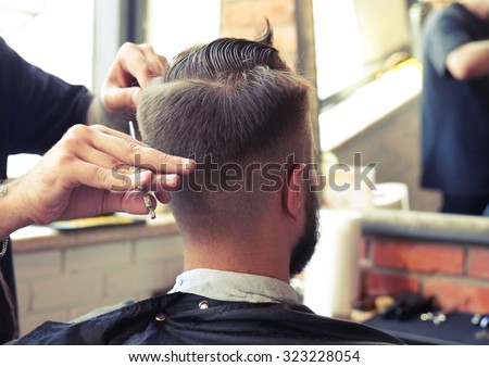 back view of man in barber shop. barber cutting hair with scissors