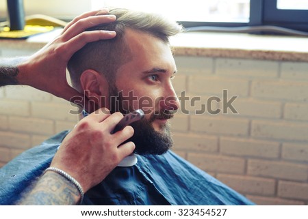 portrait of handsome man in barbershop. barber shaving man with straight razor