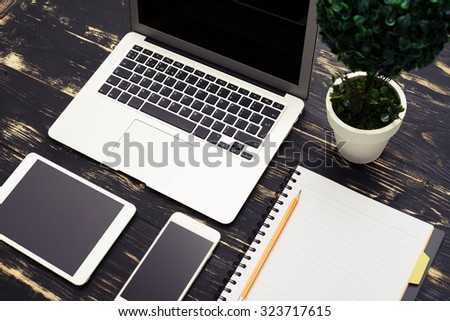 top view of workspace with laptop, smartphone, tablet pc and empty notebook