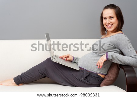 smiley pregnant woman with laptop at home