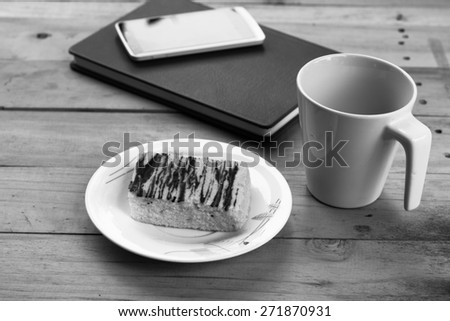 black and white notebook with coffee cup and cake on wood table