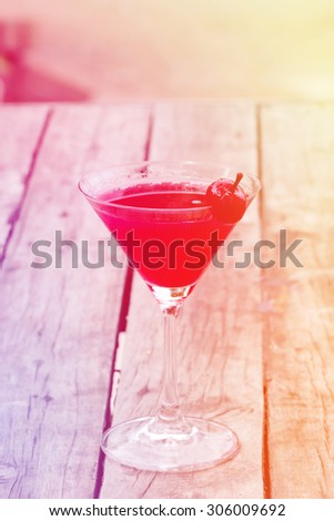 Cherry cocktail in martini glass on rustic table with vintage filter effect