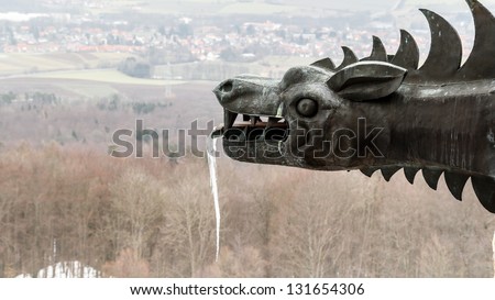 Dramatic Picture of a Frozen Medieval Dragon Statue with an Icicle on the Giechburg Castle Ruin in winter Bavaria, Germany