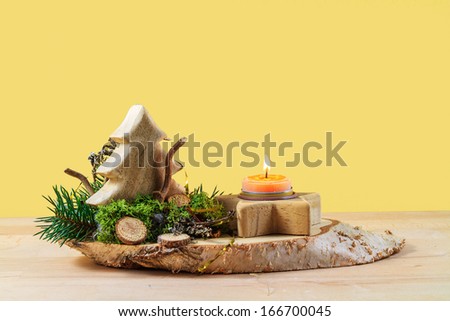 Wooden Christmas Arrangement with burning candle, isolated in front of a mono colored background