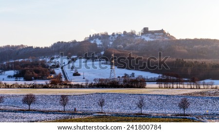 Bavarian Giechburg Winter Castle in Germany. Blue Snow and clear blue sky. Snowed Trees and Hills. Rural Countryside Landscape with low setting sun