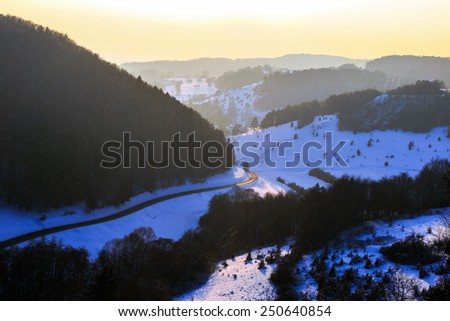 Cold snowy winter sunset in Bavaria, Germany. Sweet Solitude. White and Lonely hill Landscape. Lovely orange sunset